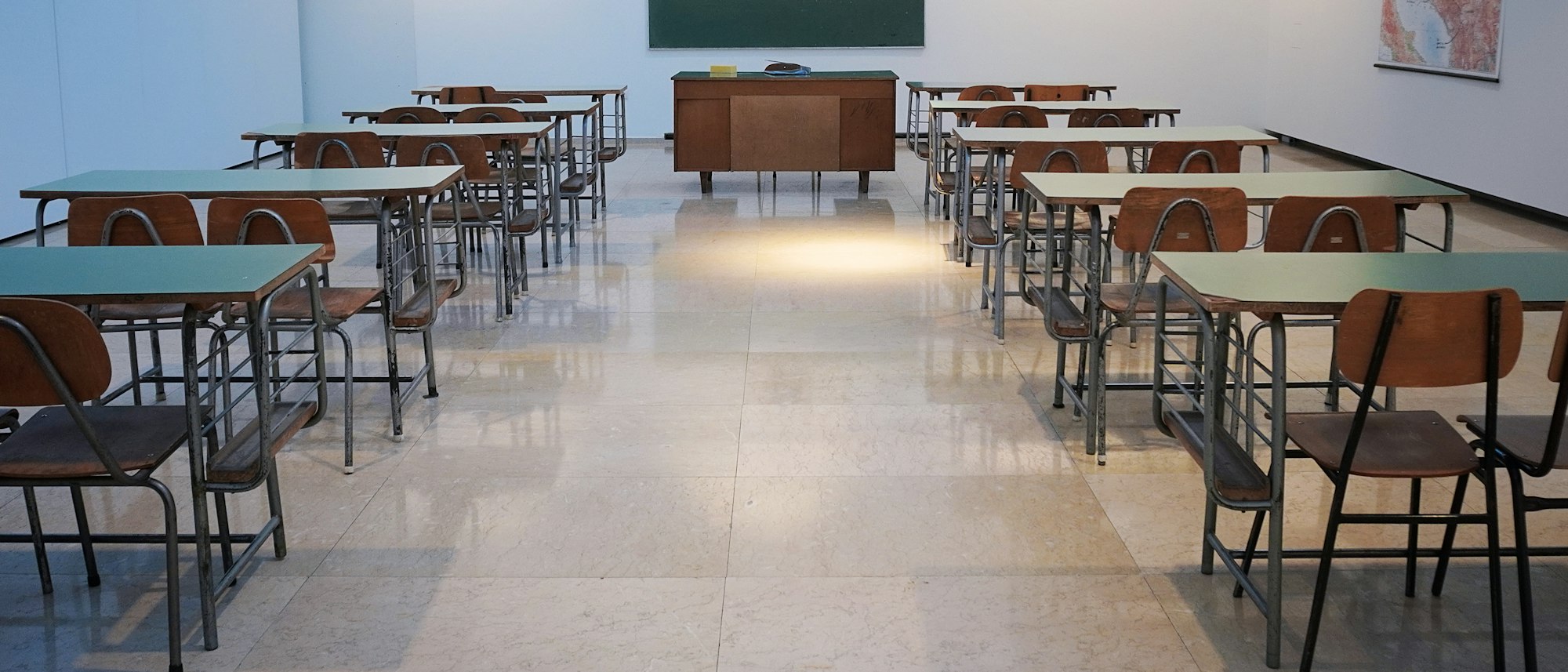 Un aula con mesas de trabajo y luz natural, sin estudiantes