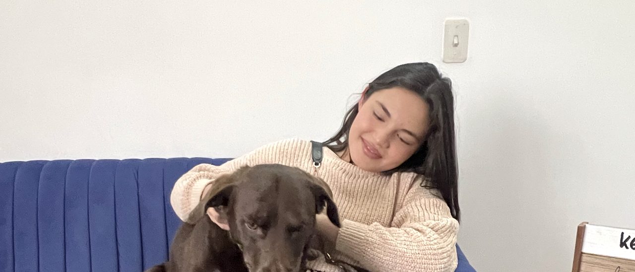 Oliva descansa sobre las piernas de una persona sentada en el sofá del consultorio
